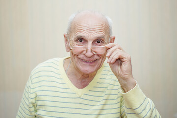 Funny and happy positive mature man looks from glasses.
