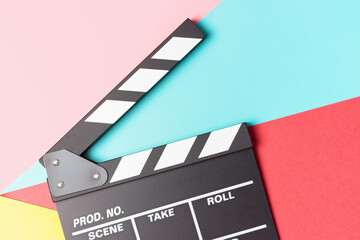 Fototapeta na wymiar The clapperboard on pink, blue and red background close-up, top view.