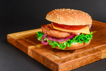 Bacon and beef patty burger with red onions and cheese over black background. Fast food, junk food concept.