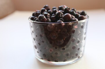 eating blueberry or currant berries in a glass glass on a white light background with a place to text the view from the side