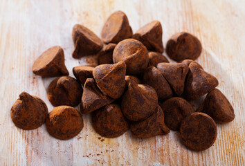 Obraz premium Group of chocolate truffle candies sprinkled with cocoa powder on wooden table..