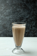 Glass of chocolate milkshake on white wooden table