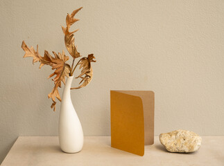 Mock up invitation brown cards and exotic Philodendron dry leaves in modern vase on marble table...