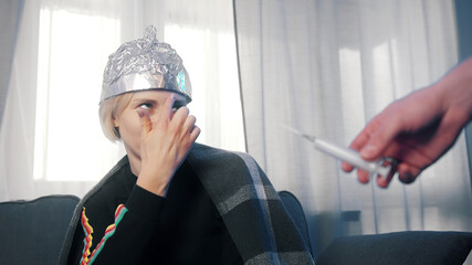 Woman with aluminum foil refusing covid-19 vaccine. Conspiracy theory about the connection between covid-19 outbreak and 5g network. High quality photo - obrazy, fototapety, plakaty