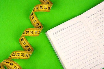 Yellow tape measure centimetric with paper note on green background