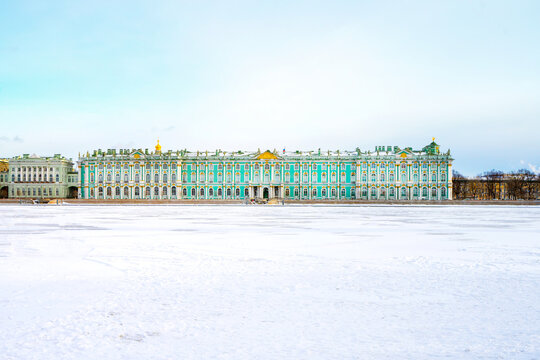 View of the Hermitage (Winter Palace) from the embankment of St. Petersburg from the icy Neva River, people walk along the river in early spring
