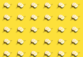 A pattern with slices of fresh pear cut in half on a yellow background. Fruit template.