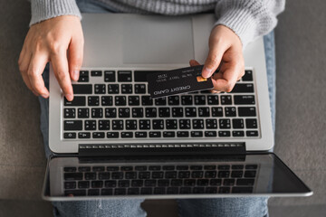 Top view of hands women siting on sofa and using computer laptop with credit card for shopping online at living room, new normal lifestyle, digital e-commerce concept.