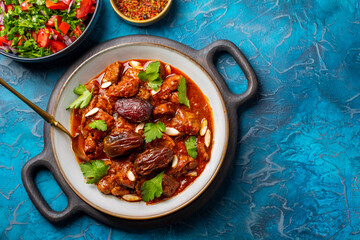 Traditional Moroccan lamb tagine simmered in spices, with dates and almonds. Salad and spices. Blue...