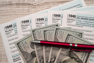 Naklejka premium 1040 US tax form with pen and dollars on desk