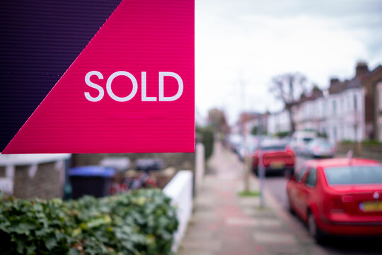Estate agent SOLD sign on street of houses