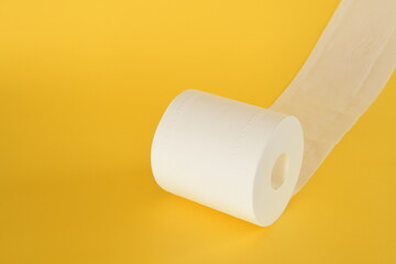 Roll of toilet paper on yellow background.