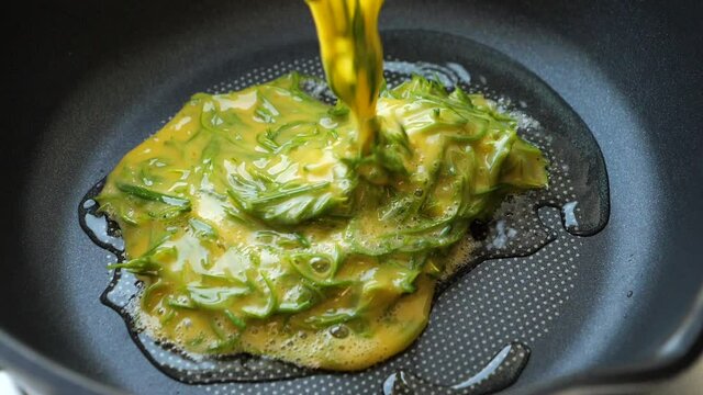 Slow motion of falling Acacia Pennata egg into the iron pan for cooking the Climbing Wattle fried egg.