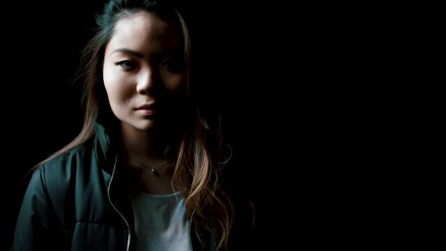 Portrait of young woman against black background