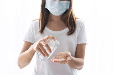 Asian woman wearing medical mask apply alcohol antiseptic gel on to her hand to prevent against infection of Covid-19 pandemic.