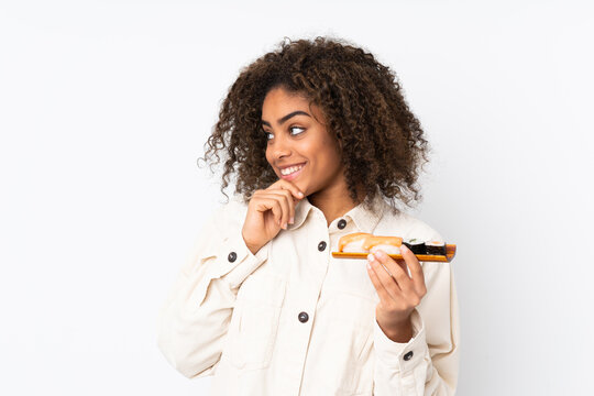 Young African American woman holding sushi isolated on white background thinking an idea and looking side