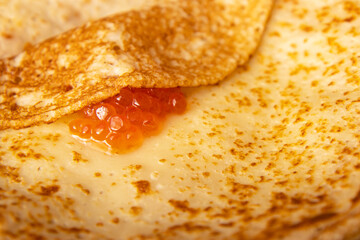 hot pancakes on a plate with red caviar as background