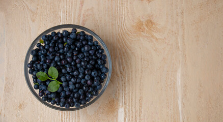 sweet forest blueberries in a saucer on the table, top view with place for text