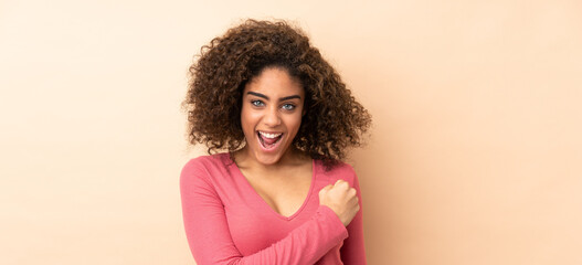 Young African American woman isolated on beige background celebrating a victory