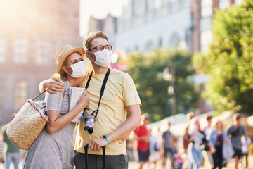 Happy tourists sightseeing in masks during summer holidays