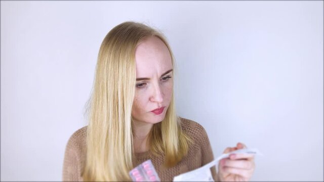 The girl on a white background reads the instructions for medicines. The woman looks at the list and composition of the drug. The concept of home self-medication and the study of the properties of dru