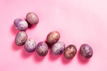 Colorful painted eggs on the pink surface. Easter flat lay with copy space. Image for greetings and invitation cards.
