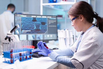 Professional scientist looking at analysis of blood tube for medical experiment. Medical woman...