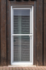 Fliegengittertür in einer Terrassentür mit Schiebegardinen an einem Haus mit Holzfassade
