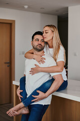 Young woman sitting at the kitchen table and hugging a man. Cute couple. Love and romantic relationship