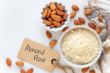 Almond flour and unpeeled almonds with a whist and an empty tag for your text. Concept of gluten free cooking and baking