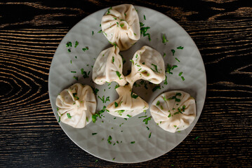 Khinkali traditional Georgian cuisine decorated with cilantro on a gray plate. Top view