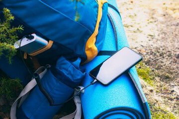Portable travel charger. Power Bank charges Smartphone against a backdrop of journey bags and...