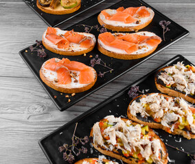 Charcuterie and cheese board with cured meat and different types of cheese. Smoked meat ot the black plate. Food board with tasty parmesan, dorblu, soft cheese, camembert.