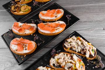 Charcuterie and cheese board with cured meat and different types of cheese. Smoked meat ot the black plate. Food board with tasty parmesan, dorblu, soft cheese, camembert.