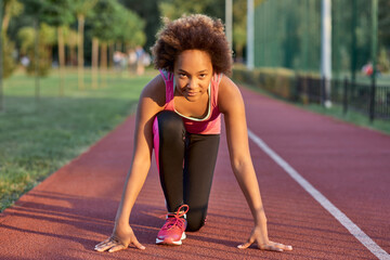 Adorable little girl standing in start position before the sprint