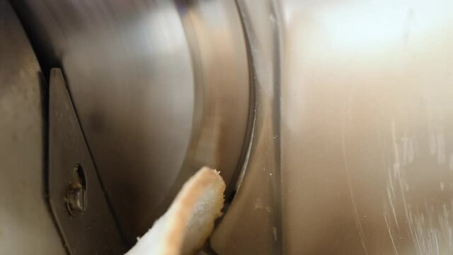 Full aluminium alloy meat slicing machine. Professional electric food slicer. Close-up of stainless steel blade cutting bread.