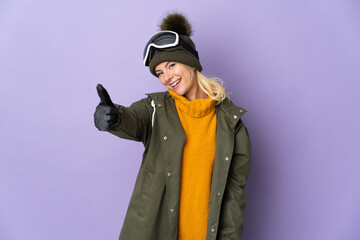 Skier Russian girl with snowboarding glasses isolated on purple background with thumbs up because something good has happened
