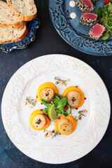 Scallop with pumpkin puree with micro-greens and pine nuts. Slices of bread. White ceramic plate....