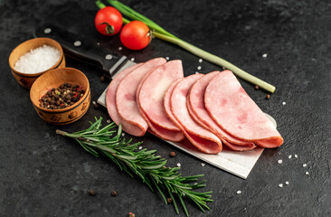 Sliced ​​ham on a knife on a stone background. Fresh prosciutto.