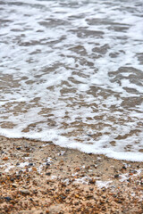 Fototapeta na wymiar rocks in the sand on the beach with foamy waves