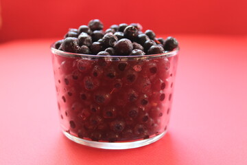 berry still life blueberries or currants in a glass on a red background with a place for text and a copyspace view from the side