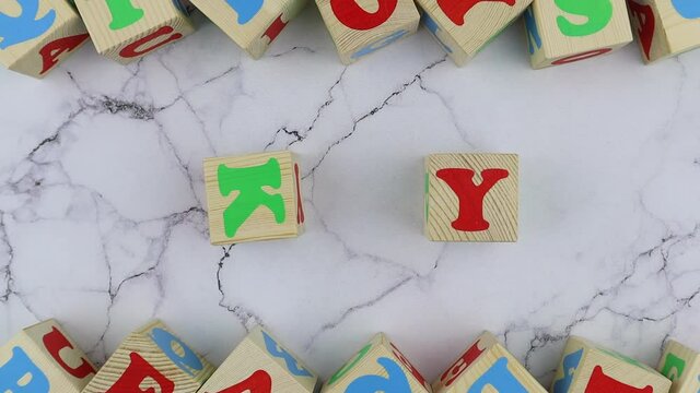 Sky concept with colorful alphabet letters on wooden cubes centered between top and bottom borders of additional alphabet blocks on a marble background. Stop motion, top view