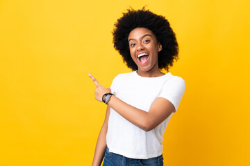 Young African American woman isolated on yellow background surprised and pointing side