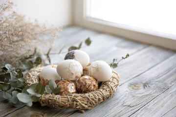 Easter composition with festive eggs in a decorative nest close up.