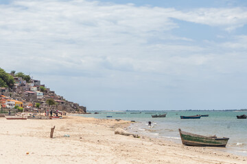 Fototapeta na wymiar Beach view with fishermen and traditional Angolan boats, in Luanda beach, ghetto as background