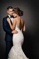 Wedding Couple Fashion Portrait. Bride Back view and Groom embracing Woman. Black Studio Background