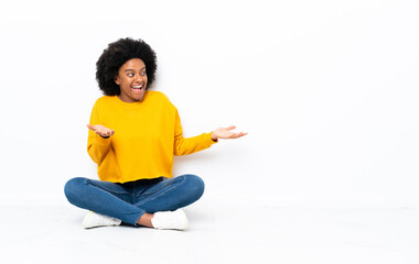 Young African American woman sitting on the floor with surprise facial expression