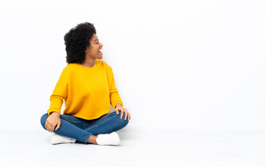Young African American woman sitting on the floor laughing in lateral position