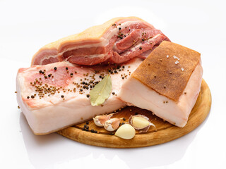 raw pork meat and lard with salt, spices and garlic on a cutting board, white background
