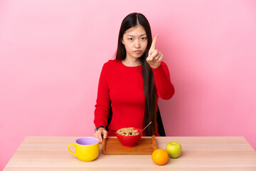 Young Chinese girl  having breakfast in a table counting one with serious expression